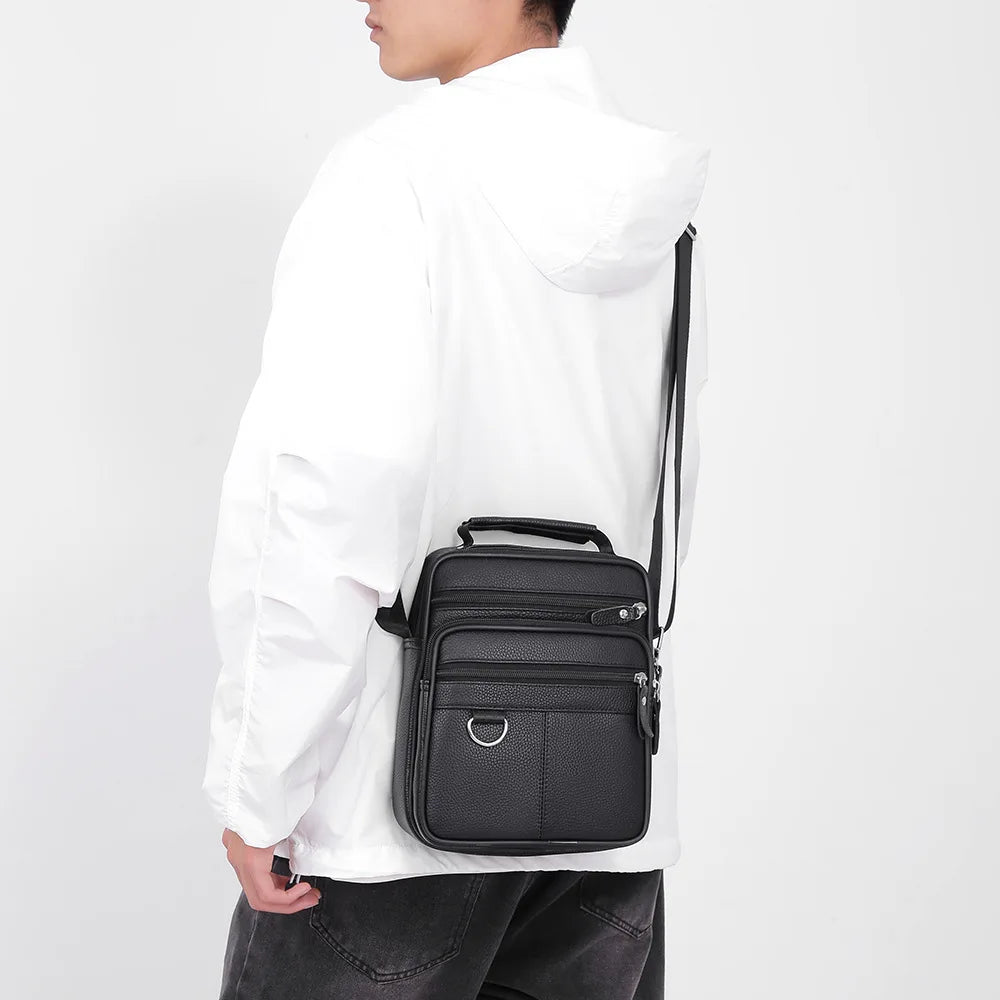 Black leather crossbody bag side view with front zip pocket and top carry handle