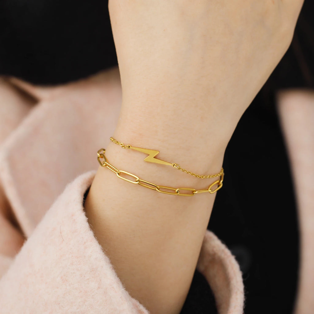 Gold-tone lightning charm bracelet with chain links, worn on wrist