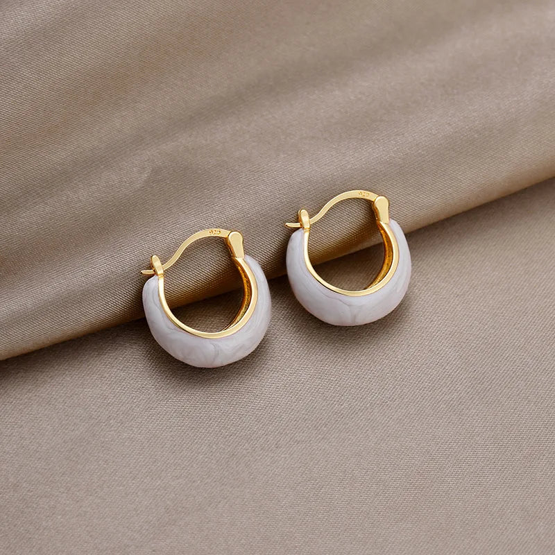 White enamel U-shaped hoop earrings with gold-tone rims and hinged closures