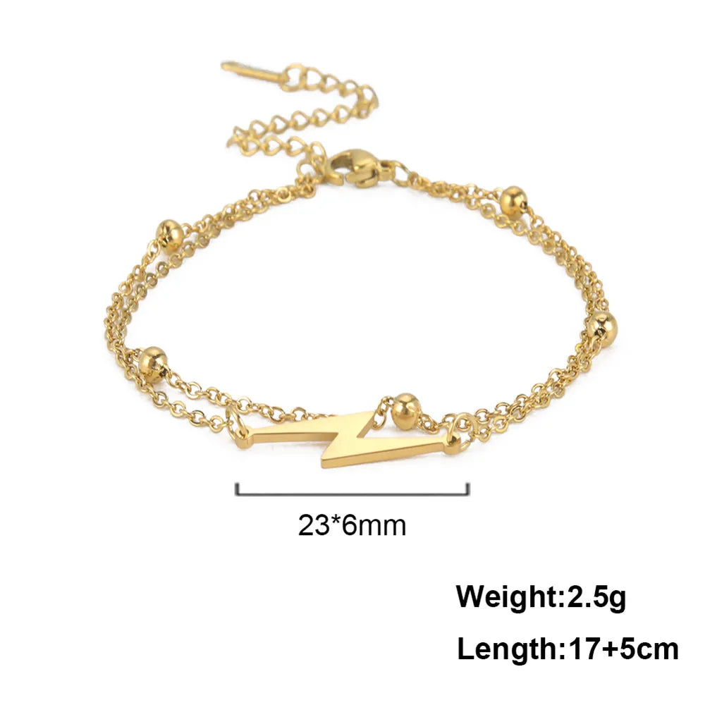 Gold chain charm bracelet with layered links and lightning bolt center charm