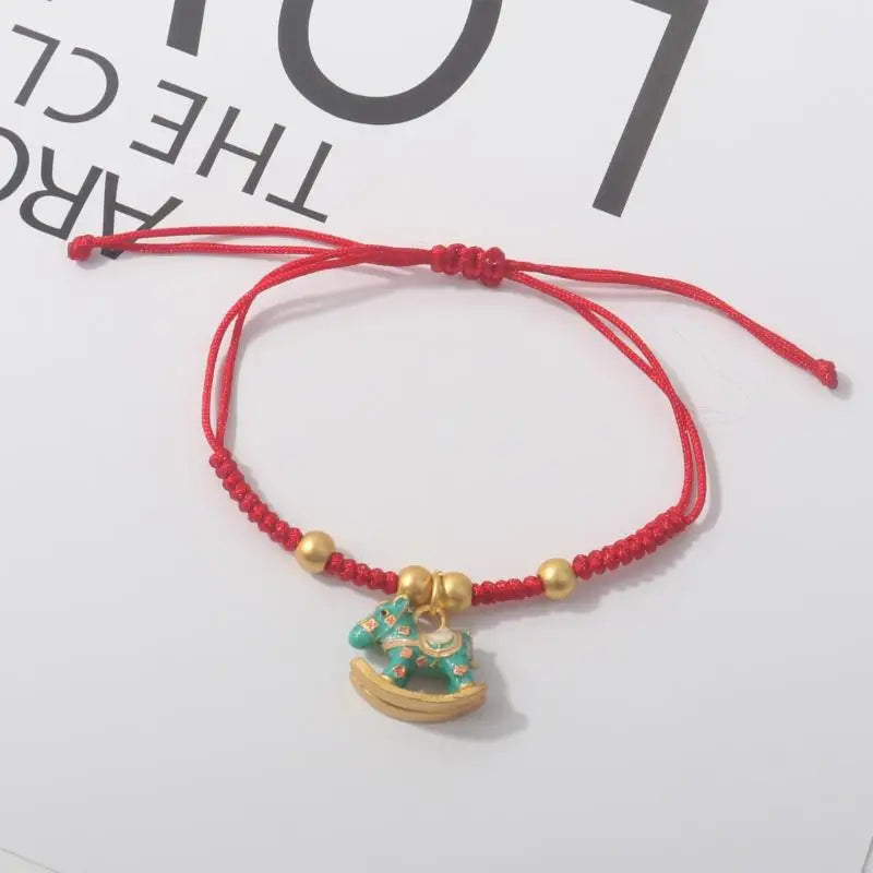 Red rope bracelet with gold beads and gold horse charm with blue-green details.