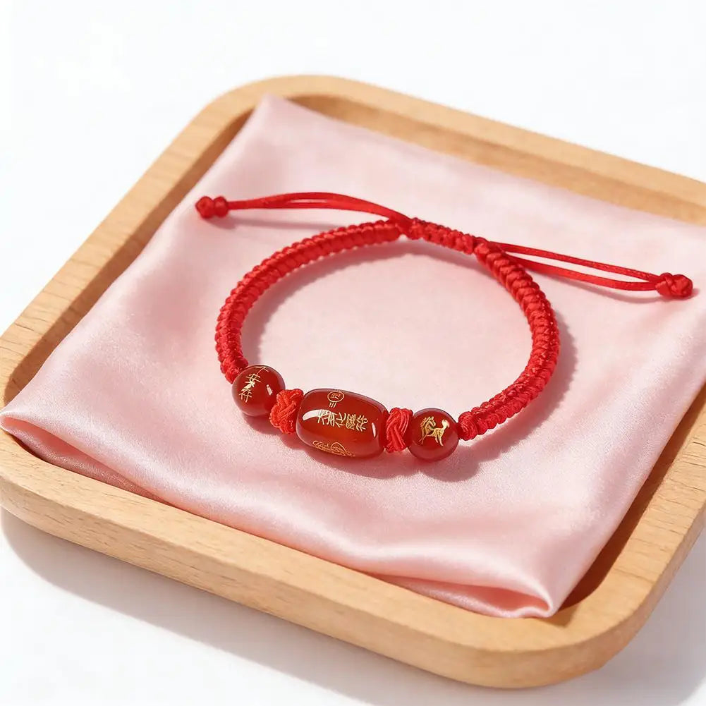 Red braided string bracelet with oval brown charm bead and side knot details