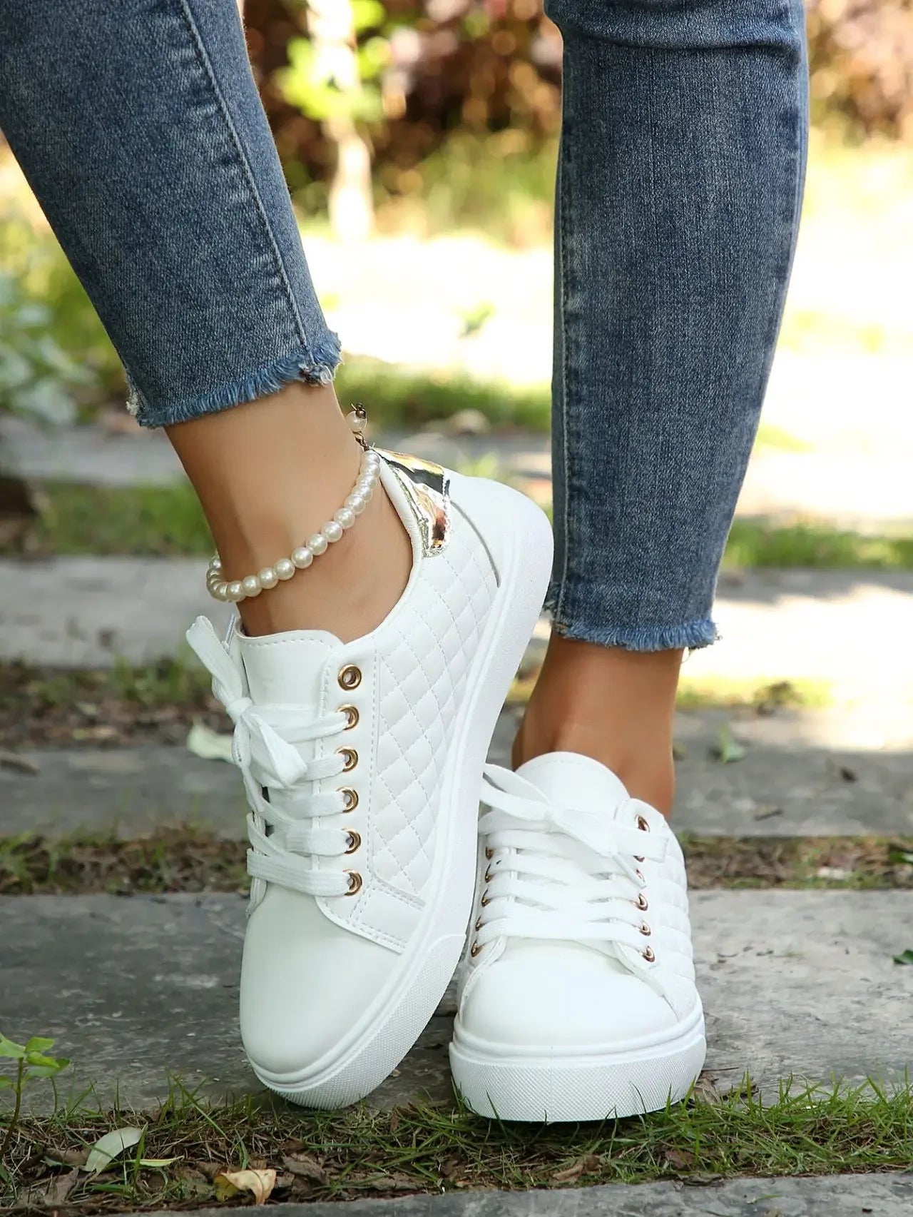 White quilted lace-up platform sneakers with gold eyelets, front view on feet.