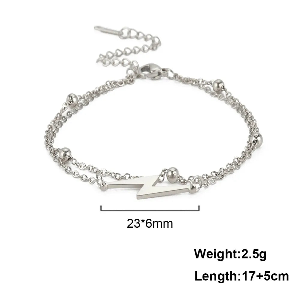 Silver tone lightning charm bracelet with layered links and white bolt pendant.