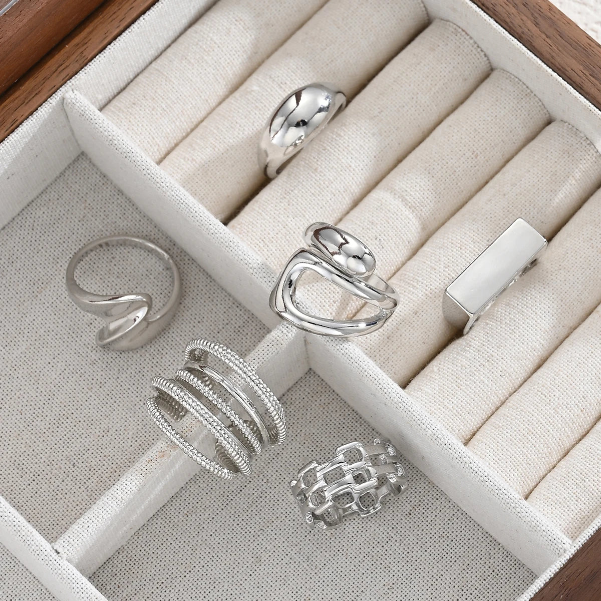 Silver-tone knuckle rings set in display box with wrapped bands and chain-link designs