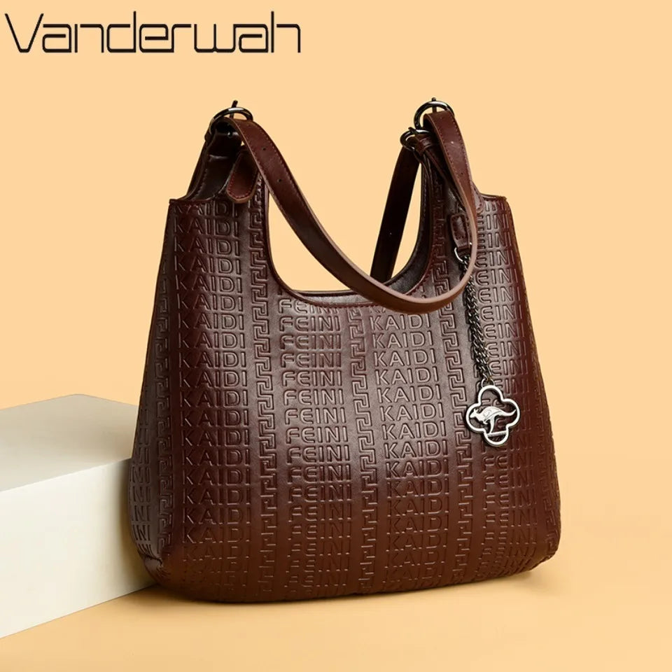 Burgundy leather shoulder bag with dual handles, embossed pattern, and clover charm