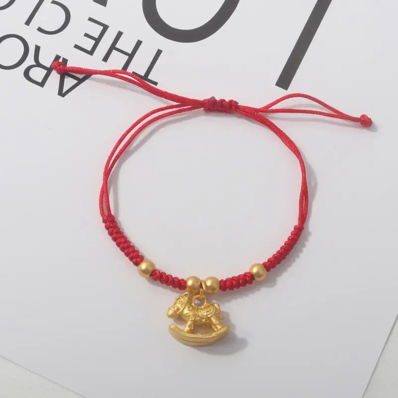 Red rope bracelet with gold beads and a seated gold horse charm
