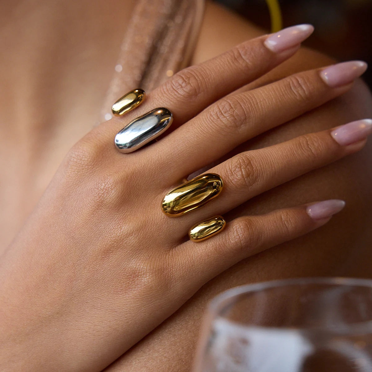 Geometric oval open rings in gold and silver tones on fingers