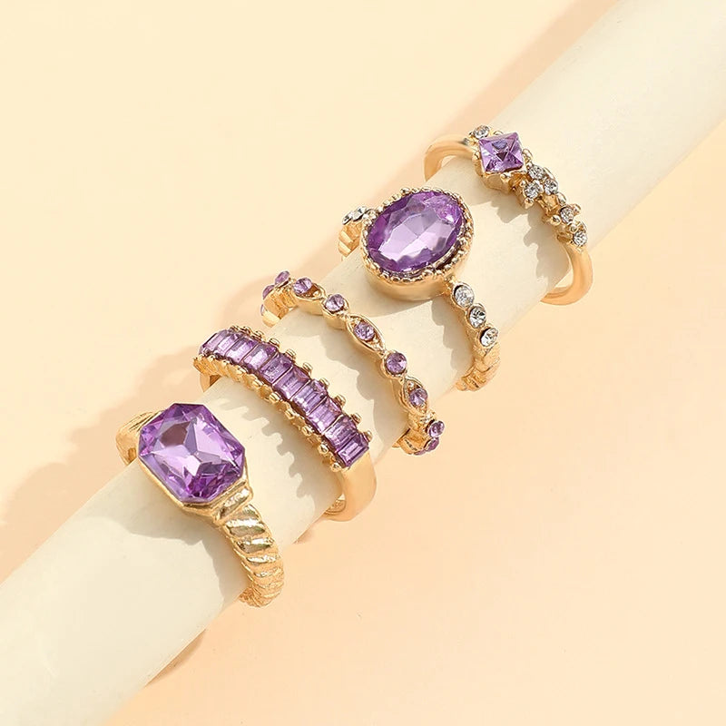 Gold-tone ring set with purple oval crystals and rhinestone rows on wrist