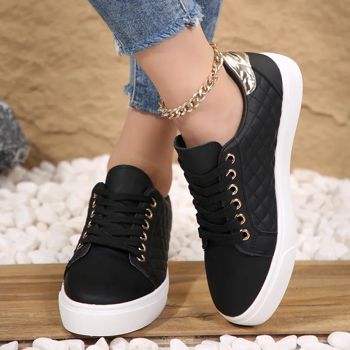 Black lace-up platform sneakers with quilted sides, gold eyelets, and white rubber sole