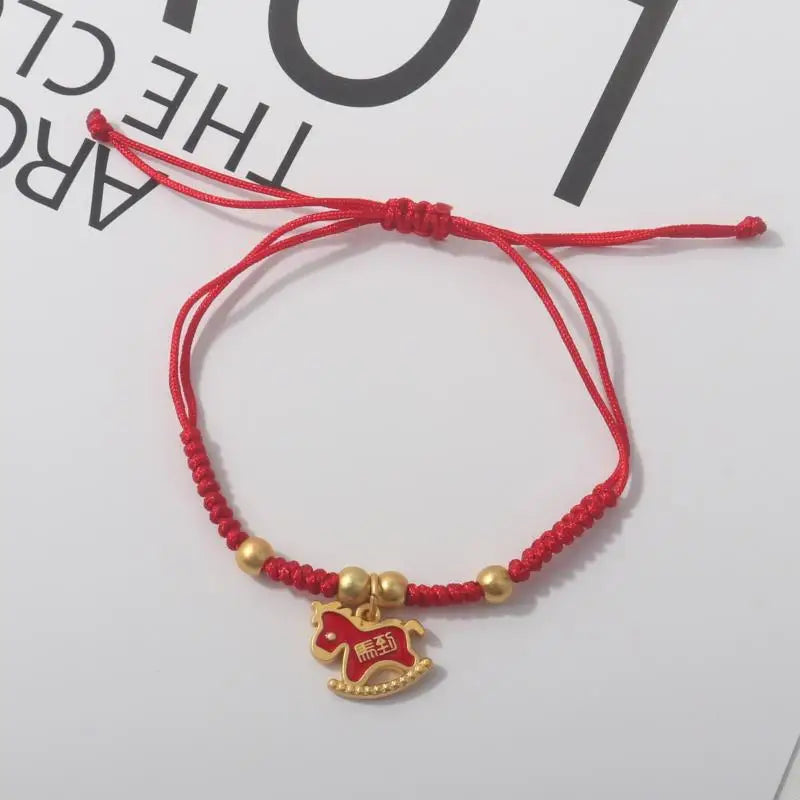 Red rope bracelet with gold beads and gold horse head charm with red details.