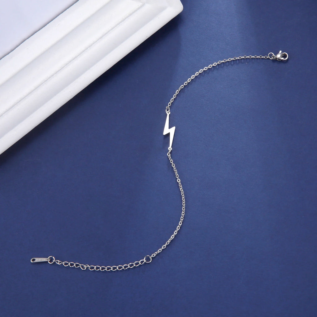 Silver tone lightning charm bracelet with small bolt charm and fine chain links.