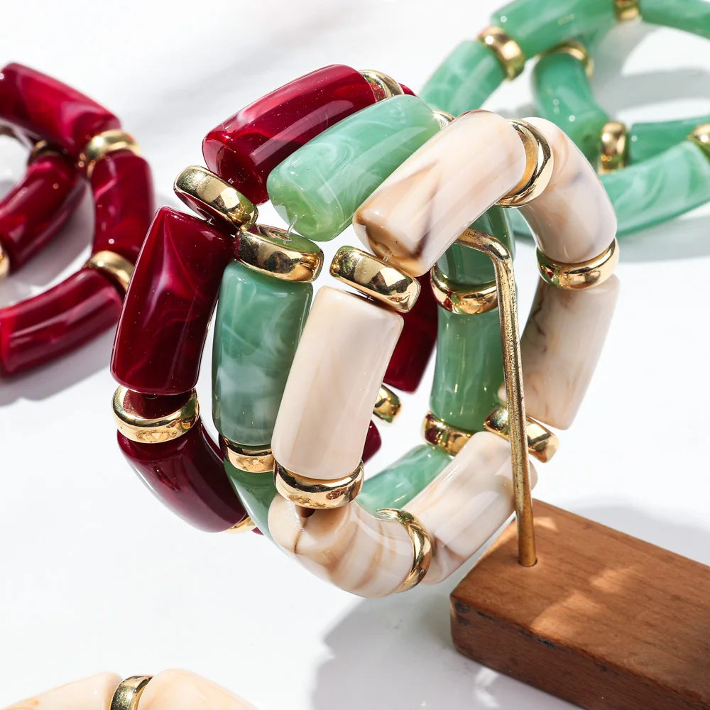 Close-up bamboo tube bead bracelets with green, ivory, and red tubes and gold-tone links