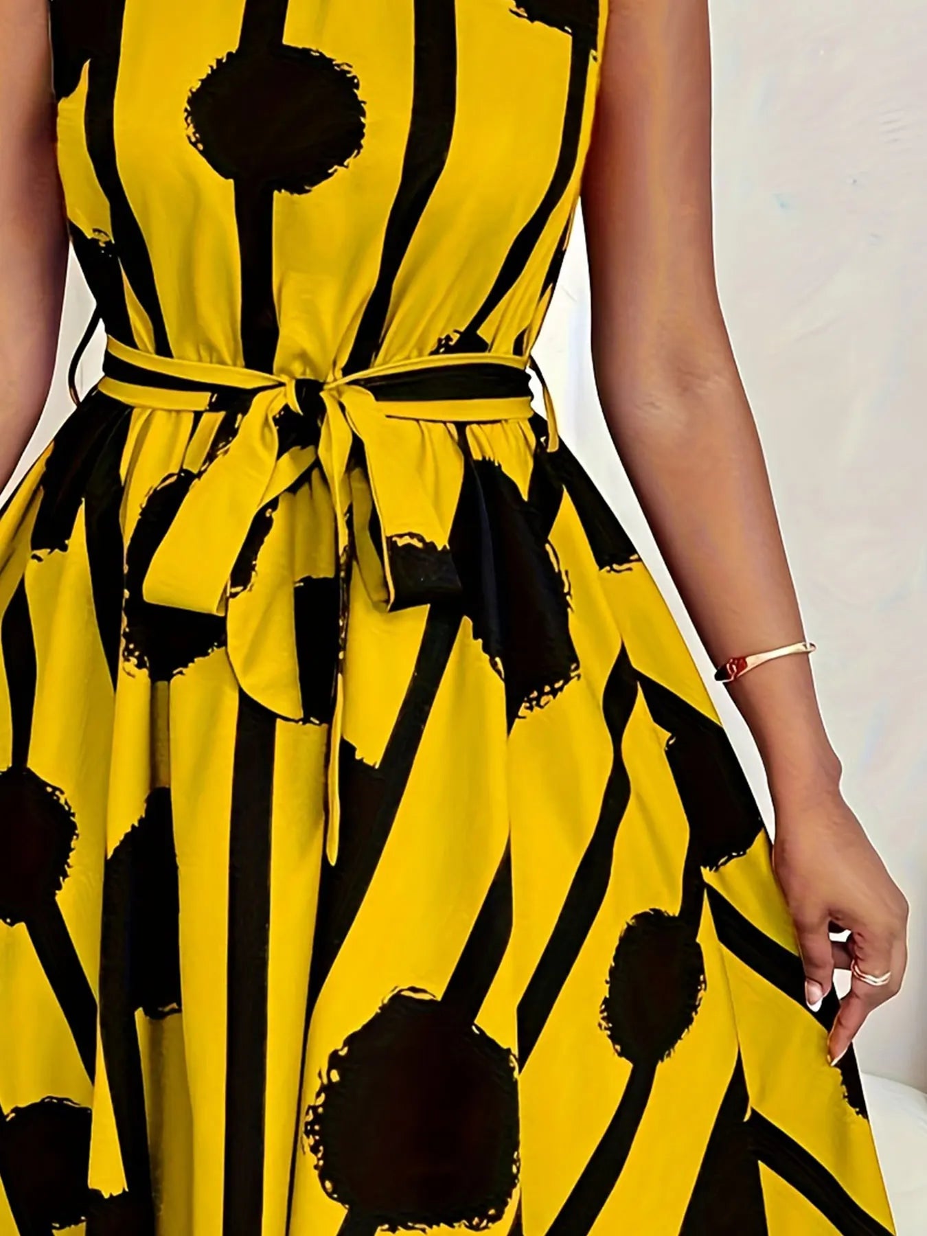 Plus-size sleeveless dress detail: V-neck and tied waist, yellow with black abstract print