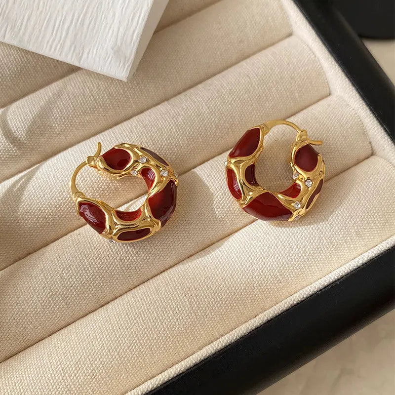 Gold-tone U-shaped hoop earrings with deep burgundy enamel and gem-like details