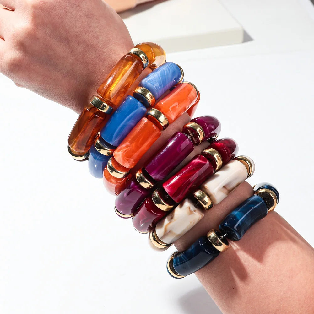 Stack of bamboo tube bead bracelets on wrist in orange, blue, red, purple, and black