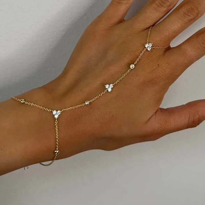 Gold rhinestone flower charm bracelet on hand with small round links and floral dangling drops