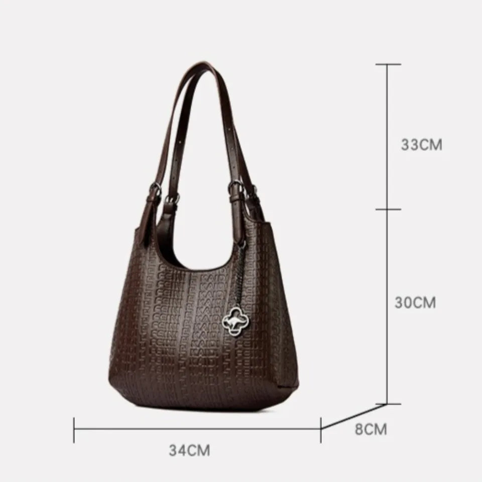 Brown leather shoulder bag with dual handles, embossed logo pattern, and clover charm