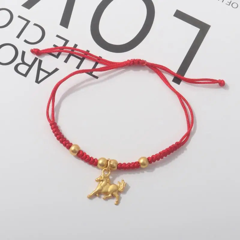 Red rope bracelet with gold beads and seated gold horse charm pendant.