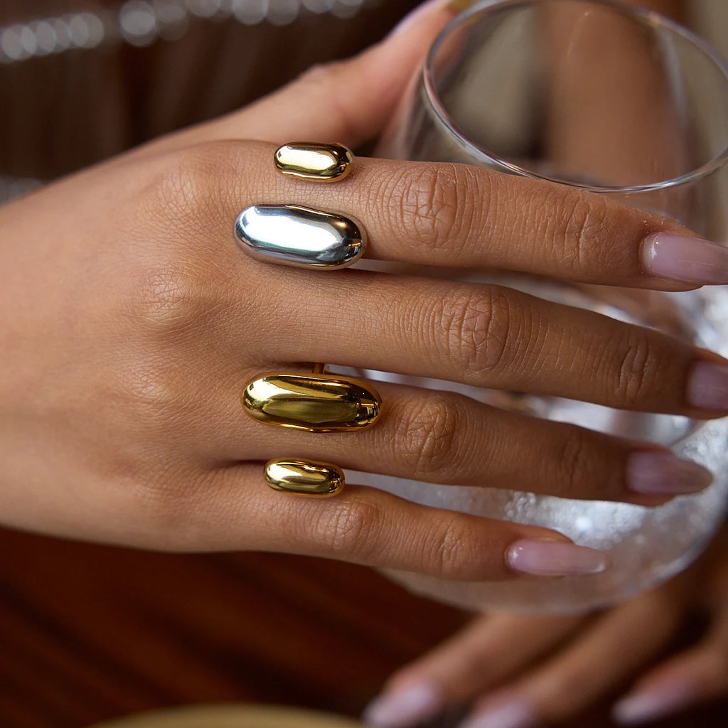 Geometric oval open rings in gold and silver tones on a hand