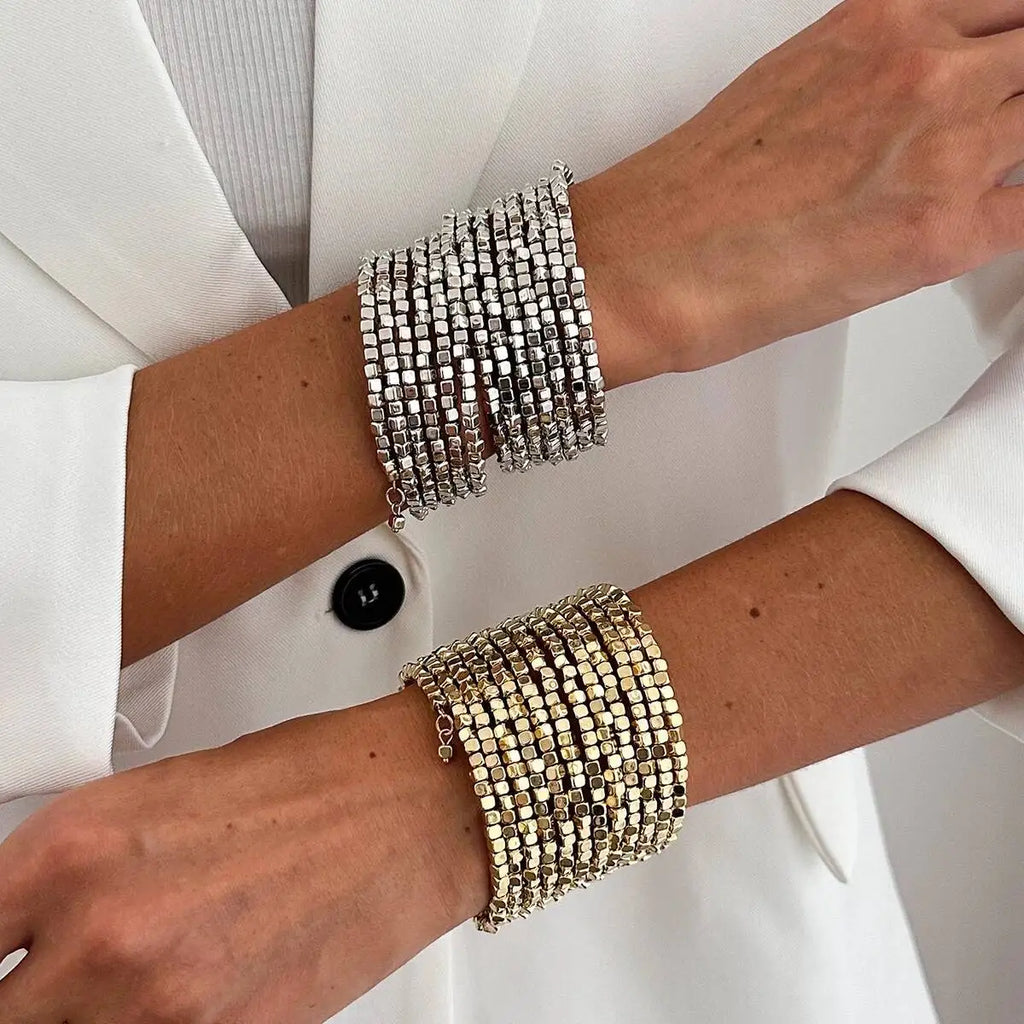 Wide multi-layer bead bangle bracelets on wrists: silver and gold square beads