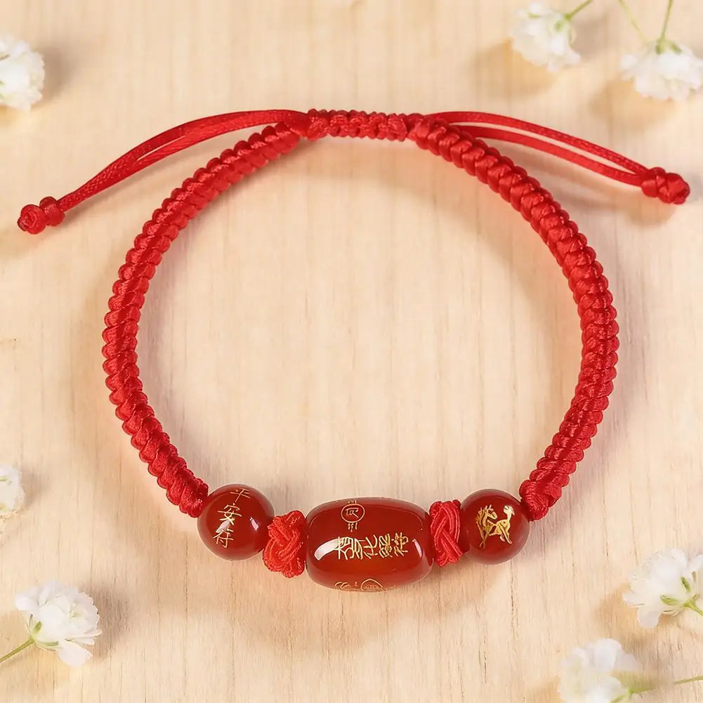 Red braided string adjustable bracelet with oval brown charm bead and horse symbols