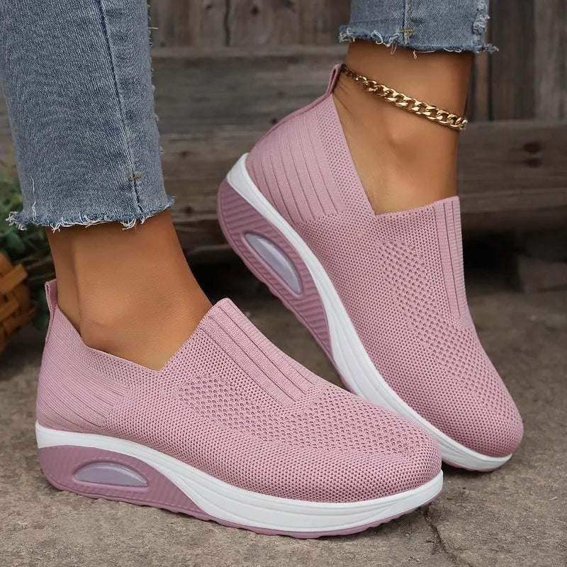 Pink slip-on platform sneakers with knit mesh upper, white outsole and oval cushion detail.