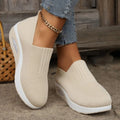 Beige slip-on platform sneakers with knit mesh upper and white outsole, ankle chain.