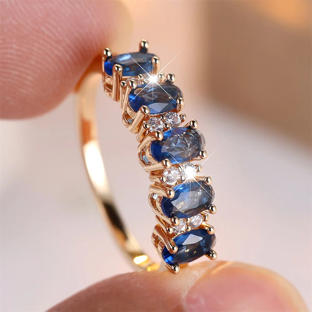 Gold-plated ring with stacked oval blue stones and clear diamond-like prong accents