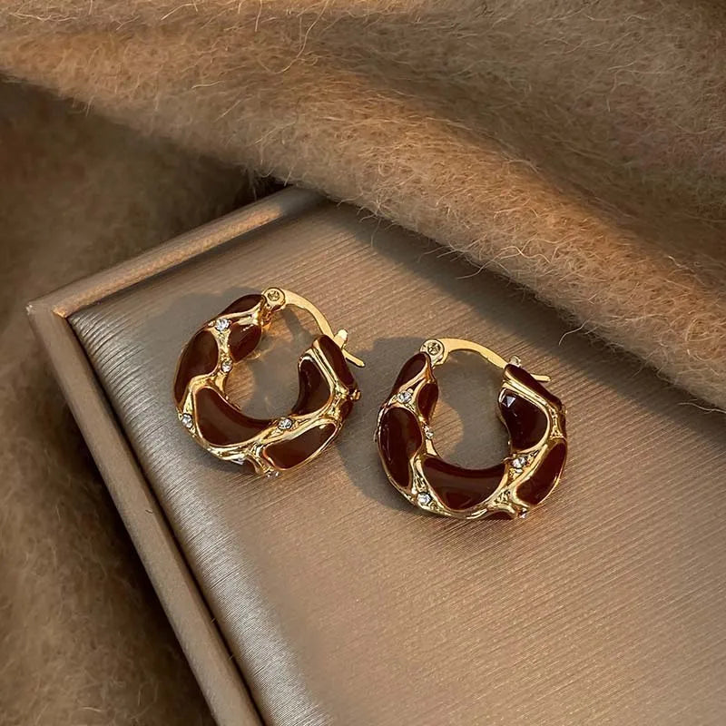 Gold-tone U-shaped hoop earrings with dark red-brown enamel round insets