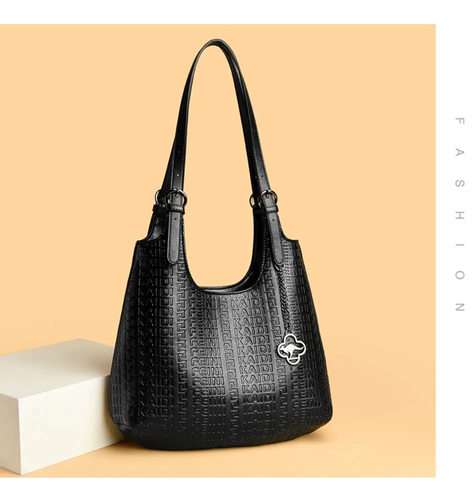 Black leather shoulder bag with dual handles, embossed logo pattern, and clover charm