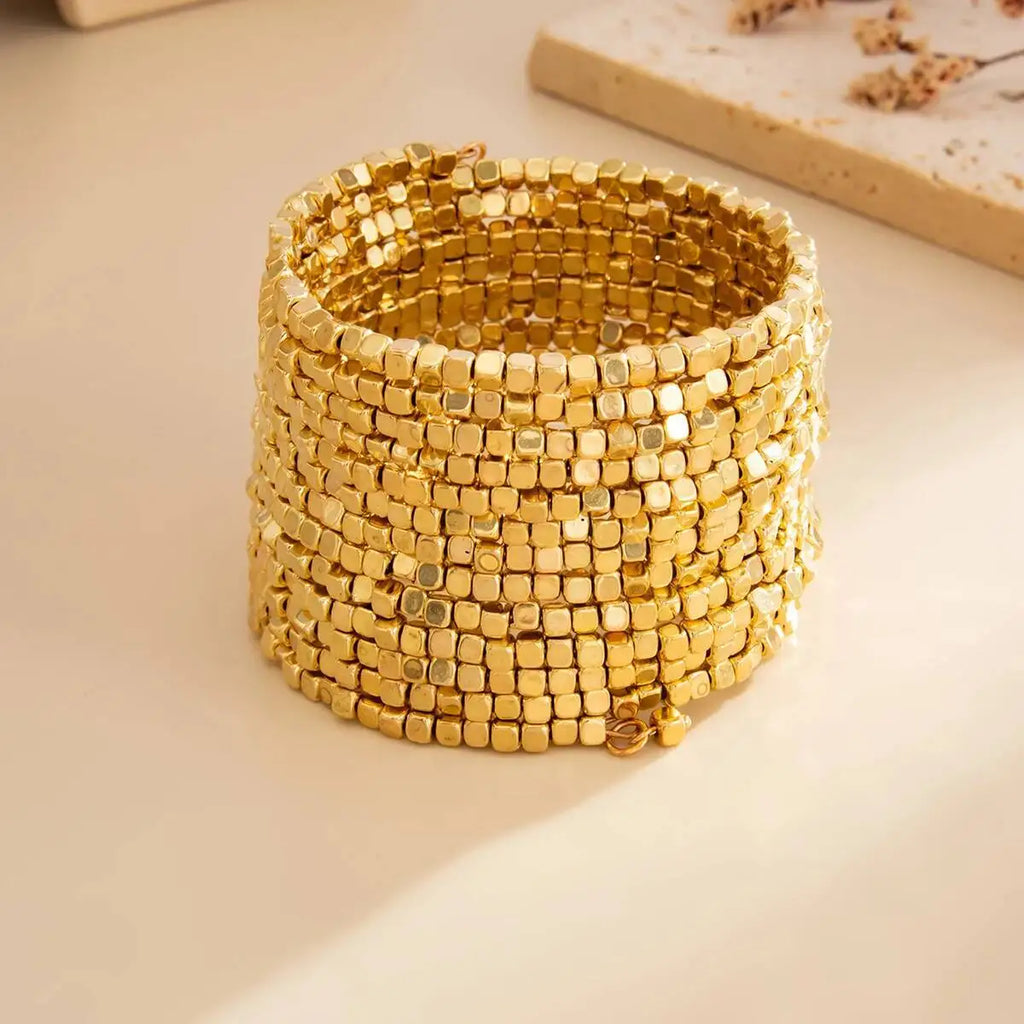 Gold-tone multi-layer wide beaded cuff bracelet with square bead rows.