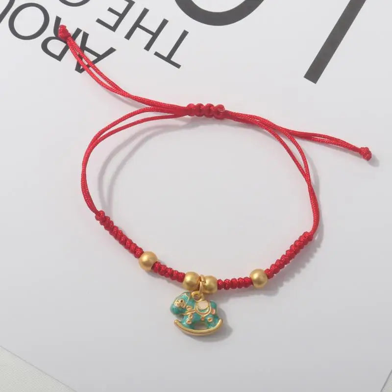 Red rope lucky bracelet with gold beads and gold-blue horse charm.